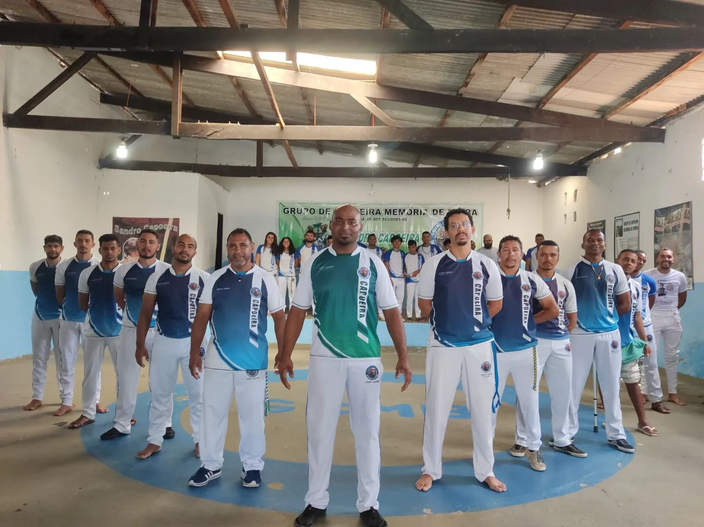 Roda de capoeira com integrantes vestidos de azul e branco
